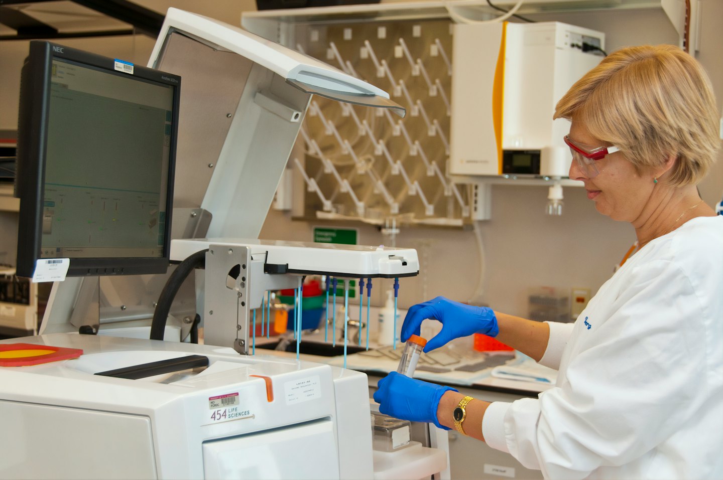 Scientist in lab coat examining a test tube with equipment.